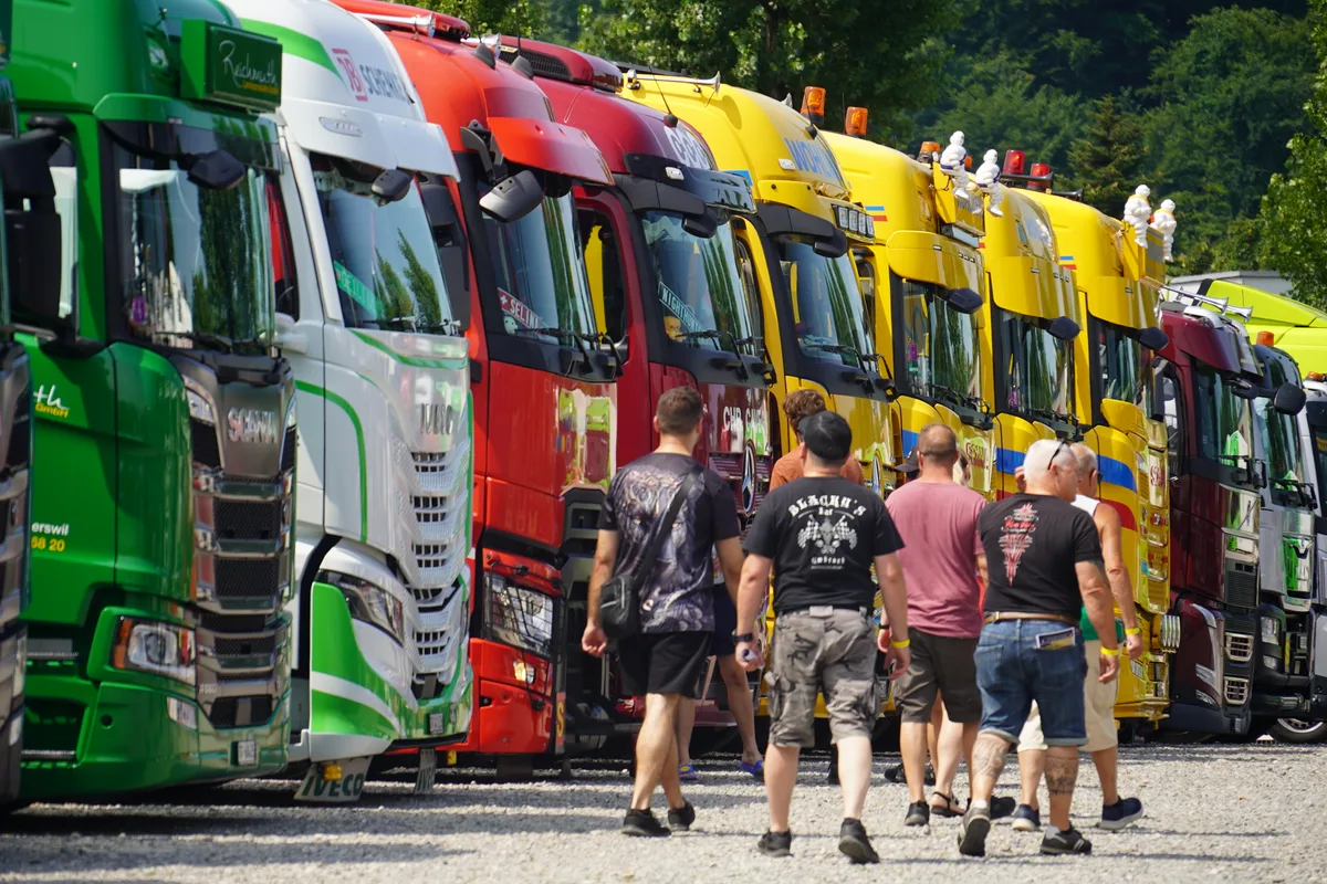 Männer die vor Trucks laufen und diese bewundern. 